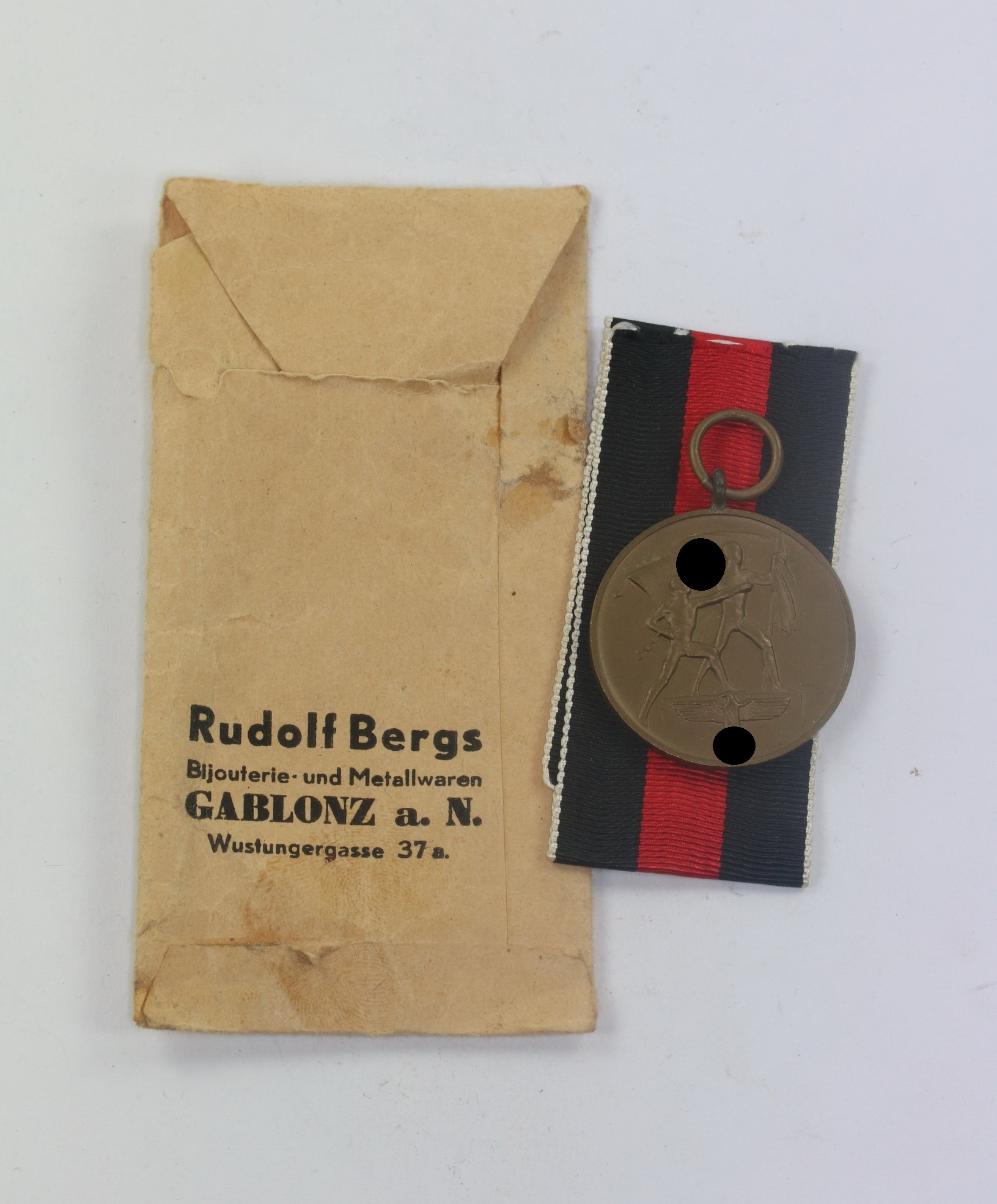 Anschlußmedaille Sudetenland, in Verkaufstüte Josef Bergs & Co. Bijouterie- und Metallwaren Gablonz a. N. – Bild 1